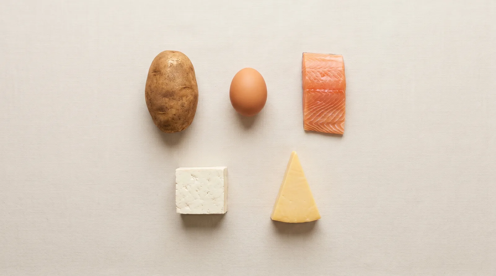 Complete-protein foods with all 9 essential amino acids: potato, egg, salmon fillet, tofu block and cheese wedge