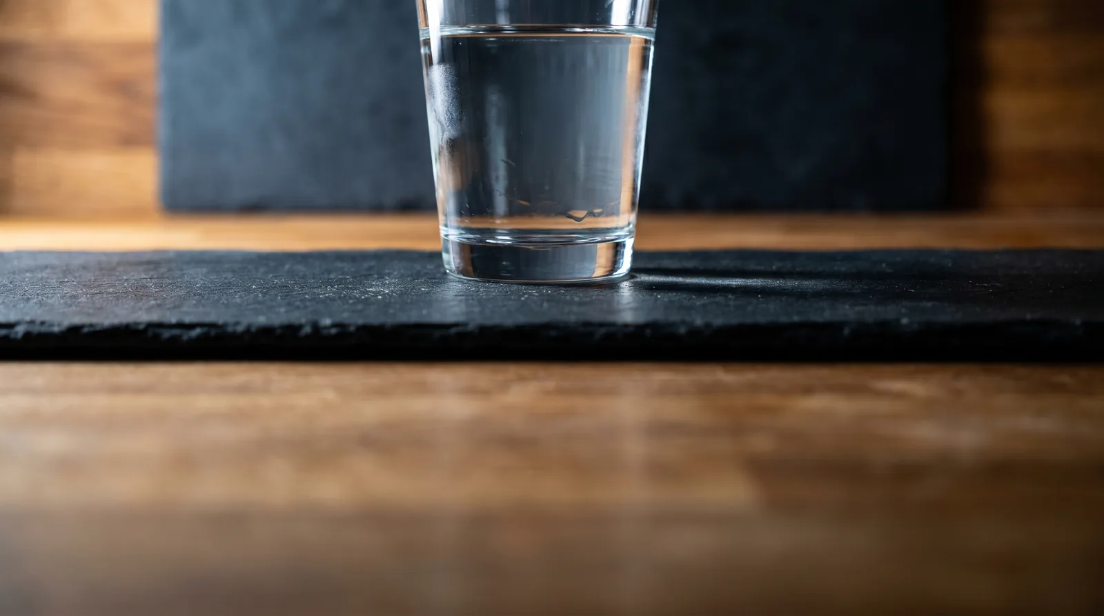 Clear glass of water on a black slate board, illustrating hydration and kidney function with protein powder